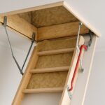 An insulated loft ladder extending from a storage space in the ceiling, showcasing wooden steps and insulation material.